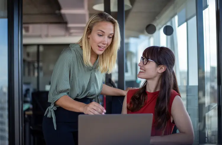 Two young professionals discuss something over a laptop.